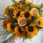 Görseldeki buket, enerjisi yüksek ayçiçekleri (günebakan), taze limon dilimleri ve minik sarı çiçekli dolgu bitkileriyle (Solidago/Altınbaşak) hazırlanmış, alışılmışın dışında, modern ve ferah bir aranjmandır. Bu tarz bir ürün için "yaz enerjisi" ve "sıra dışı tasarım" vurgusu yapmalısınız.