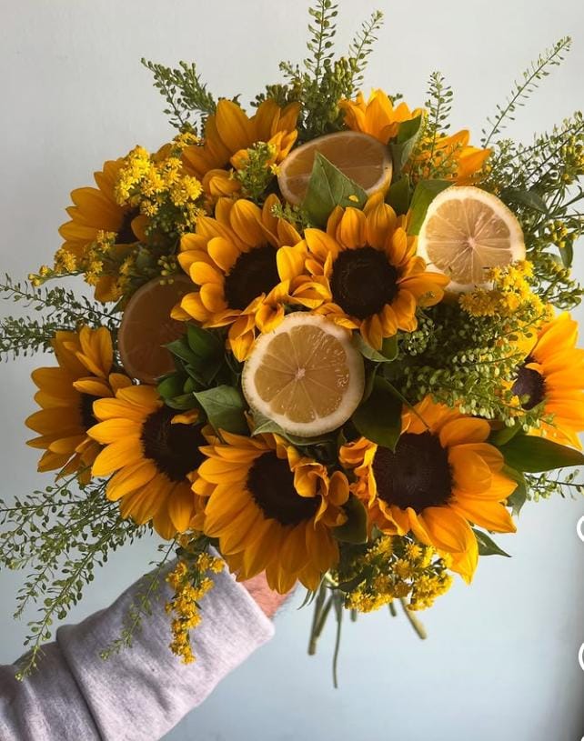 Görseldeki buket, enerjisi yüksek ayçiçekleri (günebakan), taze limon dilimleri ve minik sarı çiçekli dolgu bitkileriyle (Solidago/Altınbaşak) hazırlanmış, alışılmışın dışında, modern ve ferah bir aranjmandır. Bu tarz bir ürün için "yaz enerjisi" ve "sıra dışı tasarım" vurgusu yapmalısınız.