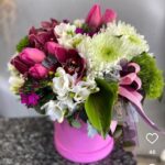 Görseldeki ürün; fuşya renkli silindir kutu içerisinde mor orkideler (Cymbidium), pembe lale ve karanfiller, beyaz krizantemler ve egzotik yeşil dokuların (Antoryum yaprağı ve yeşil karanfiller) bir araya geldiği, oldukça zengin içerikli ve enerjik bir "Box" (Kutu) aranjmanıdır. Malatya’da bu tarz kutu aranjmanları özellikle hastane ziyaretleri, ofis masaları ve doğum günleri için çok tercih ediliyor