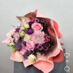 Görseldeki ürün; pudra pembesi ithal güller, iri kafalı pembe krizantemler, mor lila tonlarında mevsim çiçekleri ve minik dolgu çiçeklerinin (Anastasia/Dahlia) somon rengi katlı ambalajla birleştiği, oldukça romantik ve feminen bir bukettir. Malatya’daki internet siteniz için bu buketi "zarafet" ve "özel gün" odağında şöyle kurgulayabiliriz: